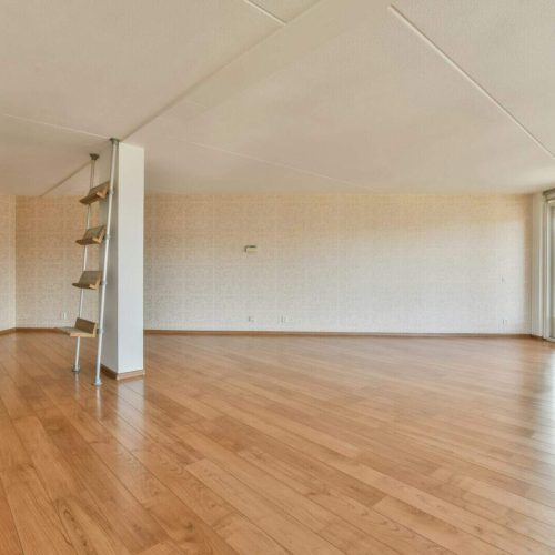 an empty living room with wood floors and a window