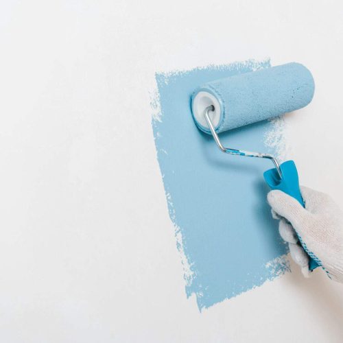 cropped view of man painting wall in blue color at home