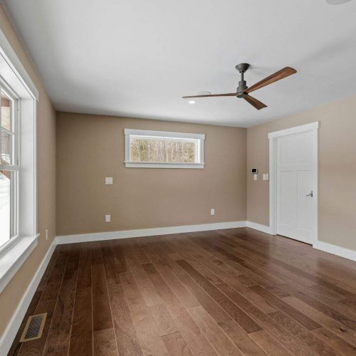 Large empty room with a ceiling fan and wood floors