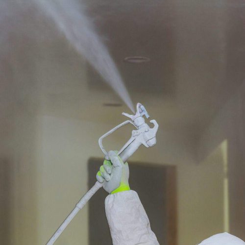 Worker painting wall with spray gun in white color hand the tool the spray of paint